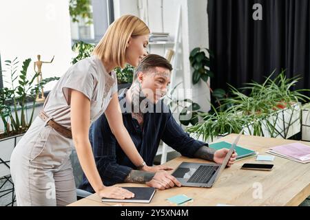 Zwei junge Fachkräfte führen an ihrem Arbeitsplatz eine Teamdiskussion mit Pflanzen um sie herum. Stockfoto