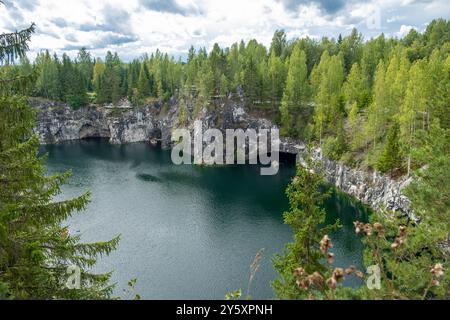 Der Marmor Canyon besticht durch tiefblaues Wasser, das von steilen Klippen und lebhaften Bäumen umgeben ist und eine friedliche Atmosphäre in Karelien bietet Stockfoto