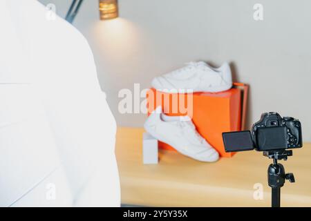 Ein professionelles Foto-Set mit stilvollen weißen Sneakers auf einem Tisch mit Digitalkamera und Beleuchtungsausrüstung, perfekt für Produktfotos Stockfoto