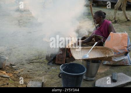 Eine Frau, die draußen Reis kocht. Das tägliche Leben in Bishnubati, einem Dorf in Santal in Sattore, Birbhum, Westbengalen, Indien. Stockfoto