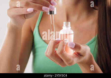 Frau, die Bio-Öl auf die Nagelhaut aufträgt, mit Pipettennaht, Handpflegekonzept, gesunden Nägeln und Haut Stockfoto