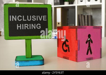 Büroschreibtisch mit einem Schild für Inclusive-Vermietung. Steht für Vielfalt am Arbeitsplatz oder gleiche Beschäftigungsmöglichkeiten. Stockfoto