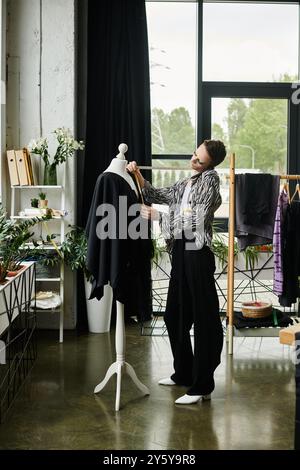 Ein kreativer Designer mit fließenden Geschlechtern formt in einer lebendigen Studioumgebung sorgfältig Stoff auf einer Kleid-Form. Stockfoto