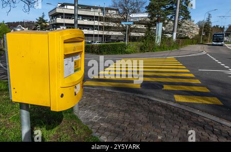 Zürich, Schweiz - 2. April 2024: Öffentlicher gelber Strassenbriefkasten in Kombination mit gelbem Zebra in der Schweiz Stockfoto