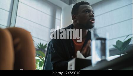 Aggressiver afroamerikanischer Mann verliert Selbstkontrolle, beginnt Streit und schreit während der Paartherapie. Multiethnische Familie mit Konflikten bei Beratungssitzungen mit Therapeuten oder Eheberater. Stockfoto