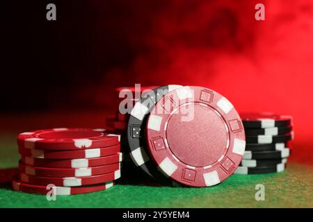 Pokerspiel. Casino Chips auf grünem Tisch in Neonlichtern, Nahaufnahme Stockfoto