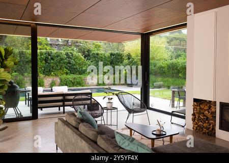 Modernes Wohnzimmer mit großen Fenstern, Blick auf den Garten und den Pool, Kopierraum Stockfoto