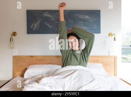Sich im Bett ausstrecken, Frau aufwachen und lächeln, morgens Entspannung genießen Stockfoto