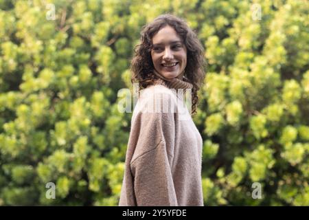 Lächelnde Frau in einem gemütlichen Pullover, der die Natur im Freien genießt Stockfoto