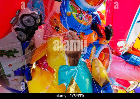 Hand einer thailändischen Verkäuferin, die während eines Festivals verschiedene bunte Ballons hält Stockfoto