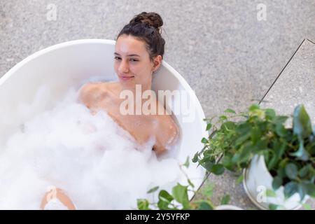 Entspannen Sie sich im Sprudelbad, Frau genießt den Spa-Tag mit Pflanzen in der Nähe Stockfoto