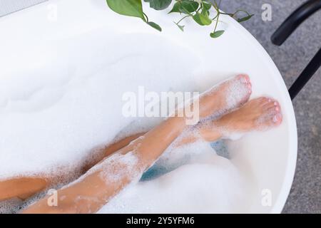 Entspannen in der Badewanne, Frau genießt Sprudelbad mit Pflanzen in der Nähe, Kopierraum Stockfoto