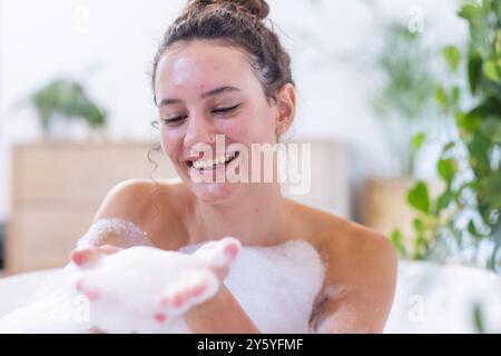 Lächelnde Frau genießt Sprudelbad, entspannt und verwöhnt sich im Spa zu Hause Stockfoto