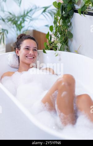 Entspannen in der Badewanne, Frau genießt Sprudelbad mit Pflanzen Stockfoto