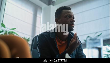 Wütender Afroamerikaner verliert seine Beherrschung, beginnt zu kämpfen und ruft während der Paartherapie. Multiethnisches junges Ehepaar mit Konflikt bei der Beratung mit Familienpsychologen. Scheidungsprozess. Stockfoto
