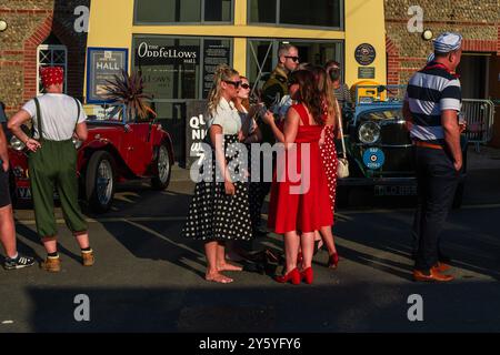 Sheringham, Norfolk, Großbritannien - 21. SEPTEMBER 2024: Gruppe der Frauen in 1940er Jahren gekleidet Vintage-rote und schwarze Kleider sprechen Stockfoto