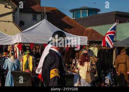 Sheringham, Norfolk, Vereinigtes Königreich – 21. SEPTEMBER 2024: Mann in Vintage-schwarzer Kleidung und Metallhelm mit Armband des Civil Defense Corps Stockfoto