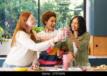 Freunde, die mit Smoothies toasten, genießen die gemeinsame Zeit in der modernen Küche Stockfoto