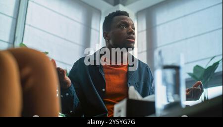 Aggressiver afroamerikanischer Mann verliert Selbstkontrolle, beginnt Streit und schreit während der Paartherapie. Multiethnische Familie mit Konflikten bei Beratungssitzungen mit Therapeuten oder Eheberater. Stockfoto