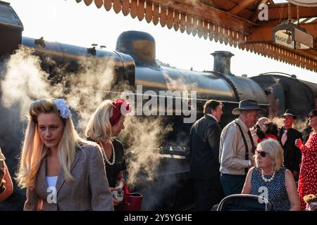 Sheringham, Norfolk, Vereinigtes Königreich - 21. SEPTEMBER 2024: Frauen in Vintage-Kleidung der 1940er-Jahre gehen am Wochenende der 1940er vor der Dampflokomotive Stockfoto
