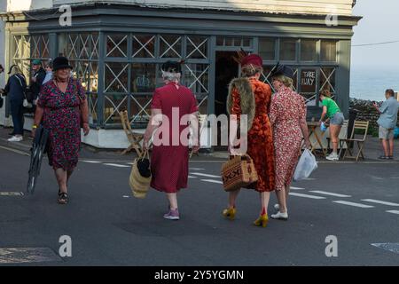 Sheringham, Norfolk, Großbritannien - 21. SEPTEMBER 2024: Foto von Frauen in eleganten Vintage-Kleidern der 1940er Jahre, die während des Wochenendes der 1940er auf der Straße sprechen Stockfoto