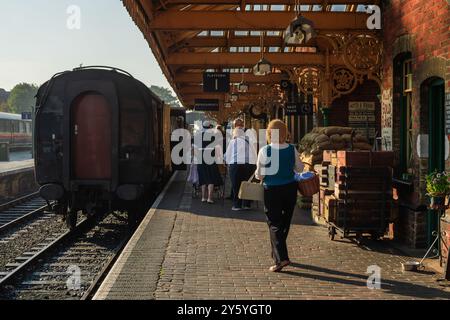 Sheringham, Norfolk, Vereinigtes Königreich - 21. SEPTEMBER 2024: Menschen mit Vintage-Kleidung der 1940er-Jahre laufen am Wochenende der 1940er-Jahre auf dem Bahnsteig neben der Dampflokomotive Stockfoto