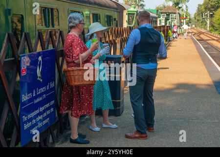 Holt, Norfolk, Großbritannien - 21. SEPTEMBER 2024: Foto von Personen, die in Vintage-Kleidung der 1940er Jahre gekleidet waren, neben einem Zugwagen Stockfoto