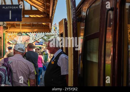 Sheringham, Norfolk, Vereinigtes Königreich - 21. SEPTEMBER 2024: Alter Mann mit weißen Haaren in klassischer Zugbegleiterkleidung aus den 1940er Jahren verlässt die Dampflokomotive durin Stockfoto