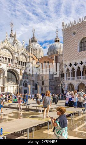 16. September 2024 - Venedig, Italien: Touristen auf der Piazza San Marco mit Palazzo Ducale und Basilika di San Marco. Hochplattformen als Laufstege Dur Stockfoto