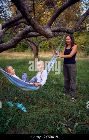 Mutter mit kleinen Töchtern, die zusammen in einer Hängematte spielen, mit Kindern zelten Stockfoto