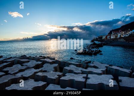 Sonnenuntergang über dem Hafen mit der Küste und schwarzen Kiesstränden in Madeira Portugal Stockfoto