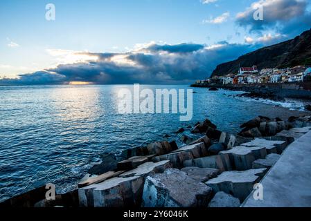 Sonnenuntergang über dem Hafen mit der Küste und schwarzen Kiesstränden in Madeira Portugal Stockfoto