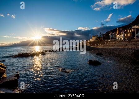 Sonnenuntergang über dem Hafen mit der Küste und schwarzen Kiesstränden in Madeira Portugal Stockfoto