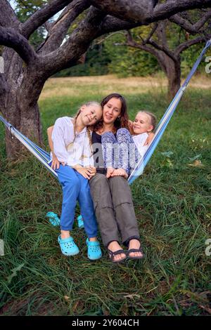 Mutter mit kleinen Töchtern, die zusammen in einer Hängematte spielen, mit Kindern zelten Stockfoto