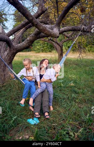 Mutter mit kleinen Töchtern, die zusammen in einer Hängematte spielen, mit Kindern zelten Stockfoto