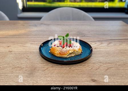 Handgemachter Hefekuchen mit Erdbeeren und Pudding, auf einem blauen Teller liegend. Stockfoto