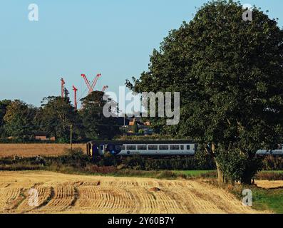 Unter dem blauen Himmel eines Herbstvormittags in West Lancashire ist ein Zug aus dem Norden gerade über einen öffentlichen Fußweg in der Nähe des Bahnhofs New Lane gefahren Stockfoto
