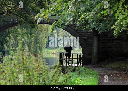 Am Sonntagmorgen laufen ein Läufer und sein Hund unter der Alder Lane Brücke über den Leeds-und Liverpool-Kanal in Parbold in West Lancashire. Stockfoto