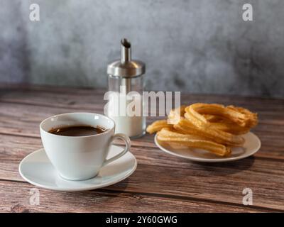 Warmes Schokoladenfrühstück in weißer Tasse mit Churros auf Holztisch Stockfoto