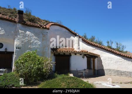 Weißes Haus mit rotem Ziegeldach und grünen Pflanzen vor einem klaren blauen Himmel, Cuevas del Zenete, Höhlenhäuser, La Calahorra, Guadix, Provinz Granada Stockfoto