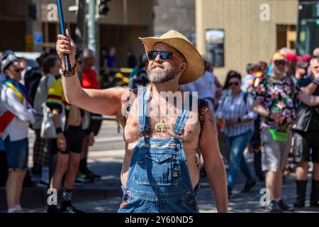 Bärtiger Mann – ein Bär – trägt Sonnenbrille, Jeansanzüge und einen Cowboyhut mit Strohhalm bei der Helsinki Pride 2024 Parade auf der Mannerheimintie in Helsinki, Finnland Stockfoto