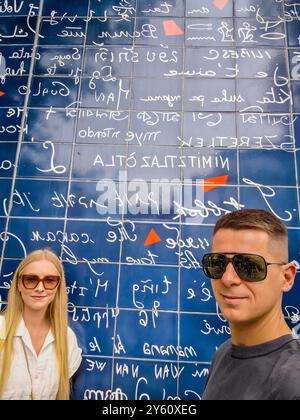 Ein junges, nettes Paar, das an der Mauer der Liebe in Montmartre Paris steht. Ich liebe dich steht in allen internationalen Sprachen drauf Stockfoto