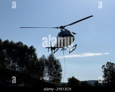 Ein Hubschrauber, der ein Paket in den Bergen des Comer Sees transportiert Stockfoto