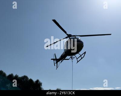 Ein Hubschrauber, der ein Paket in den Bergen des Comer Sees transportiert Stockfoto