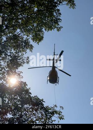 Ein Hubschrauber, der ein Paket in den Bergen des Comer Sees transportiert Stockfoto