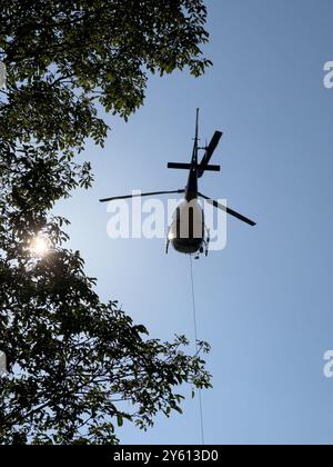 Ein Hubschrauber, der ein Paket in den Bergen des Comer Sees transportiert Stockfoto