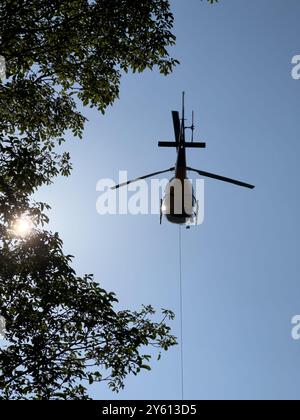 Ein Hubschrauber, der ein Paket in den Bergen des Comer Sees transportiert Stockfoto