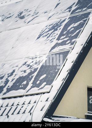 Nahaufnahme von schneebedeckten Solarpaneelen auf einem Dach, die die Herausforderung der Solarenergie unter winterlichen Bedingungen veranschaulichen. Stockfoto