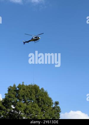 Ein Hubschrauber, der ein Paket in den Bergen des Comer Sees transportiert Stockfoto