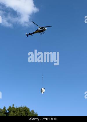 Ein Hubschrauber, der ein Paket in den Bergen des Comer Sees transportiert Stockfoto